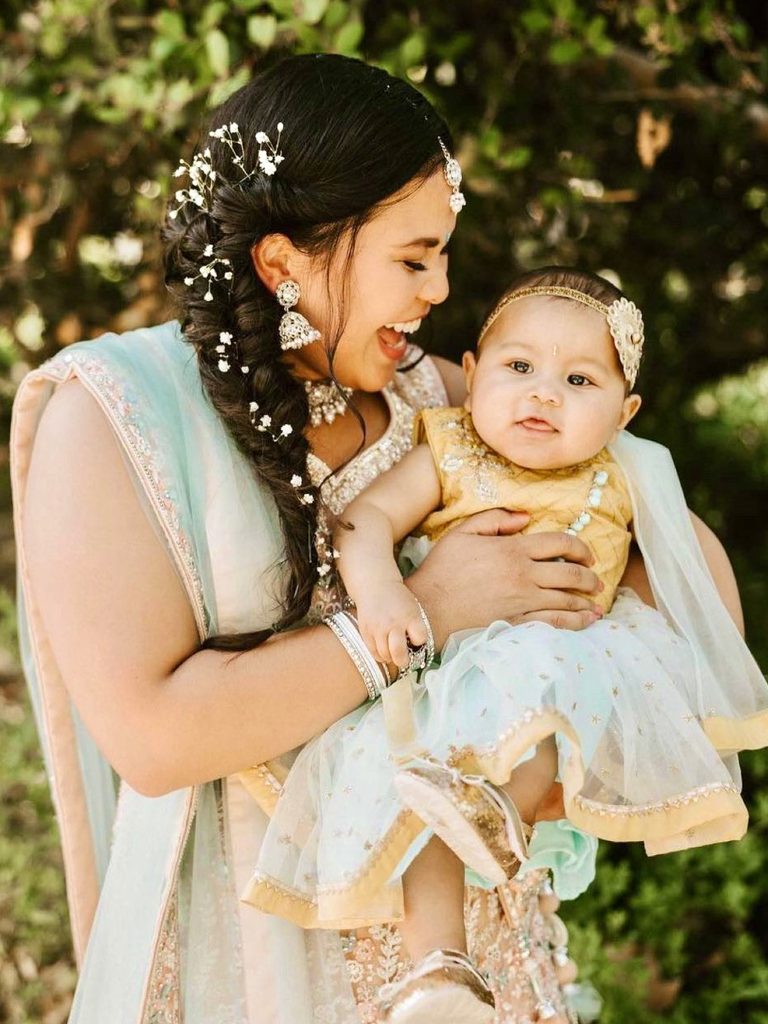 My braided style with tiny white flowers and finished makeup on a mother holding her baby.