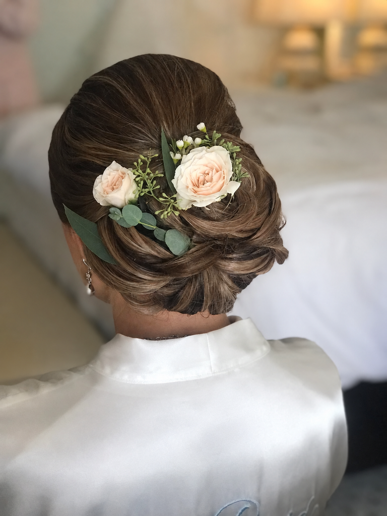 My low chignon finished with peach roses and greenery, viewed from behind.