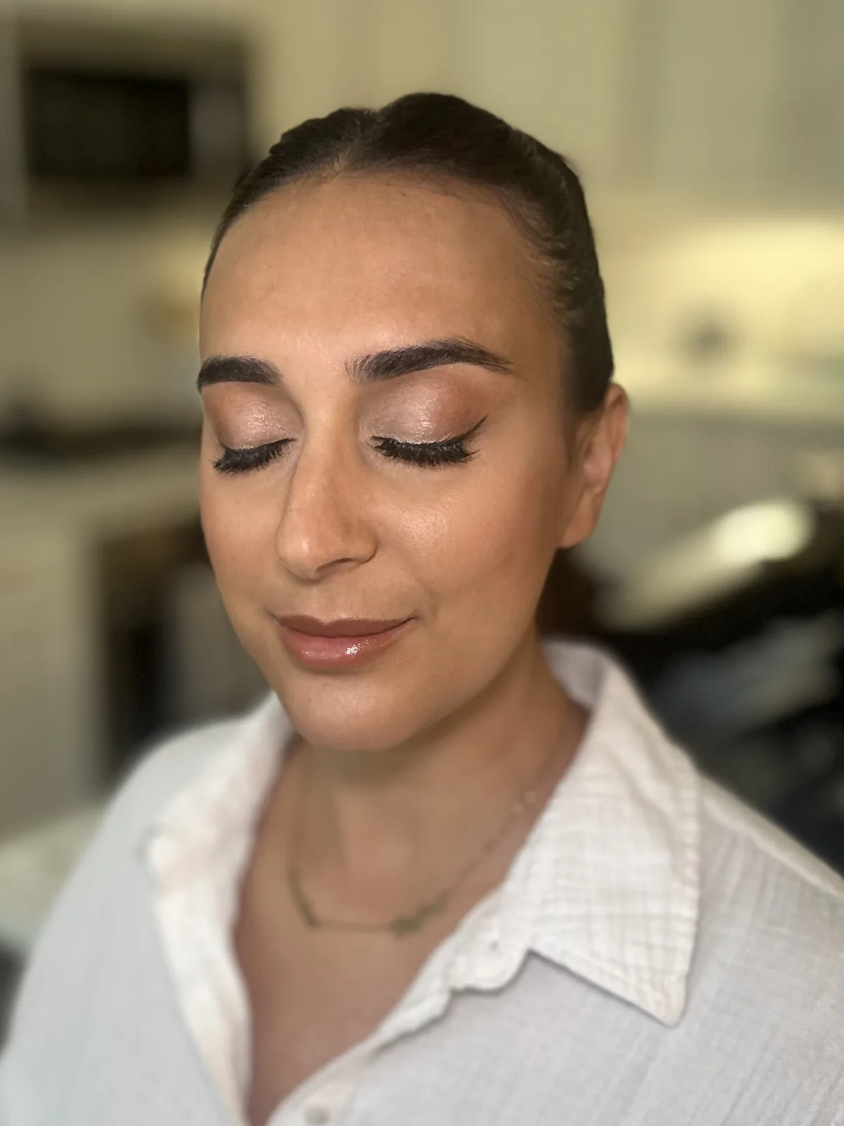 My softly highlighted makeup and middle-part ponytail on a client with her eyes closed.