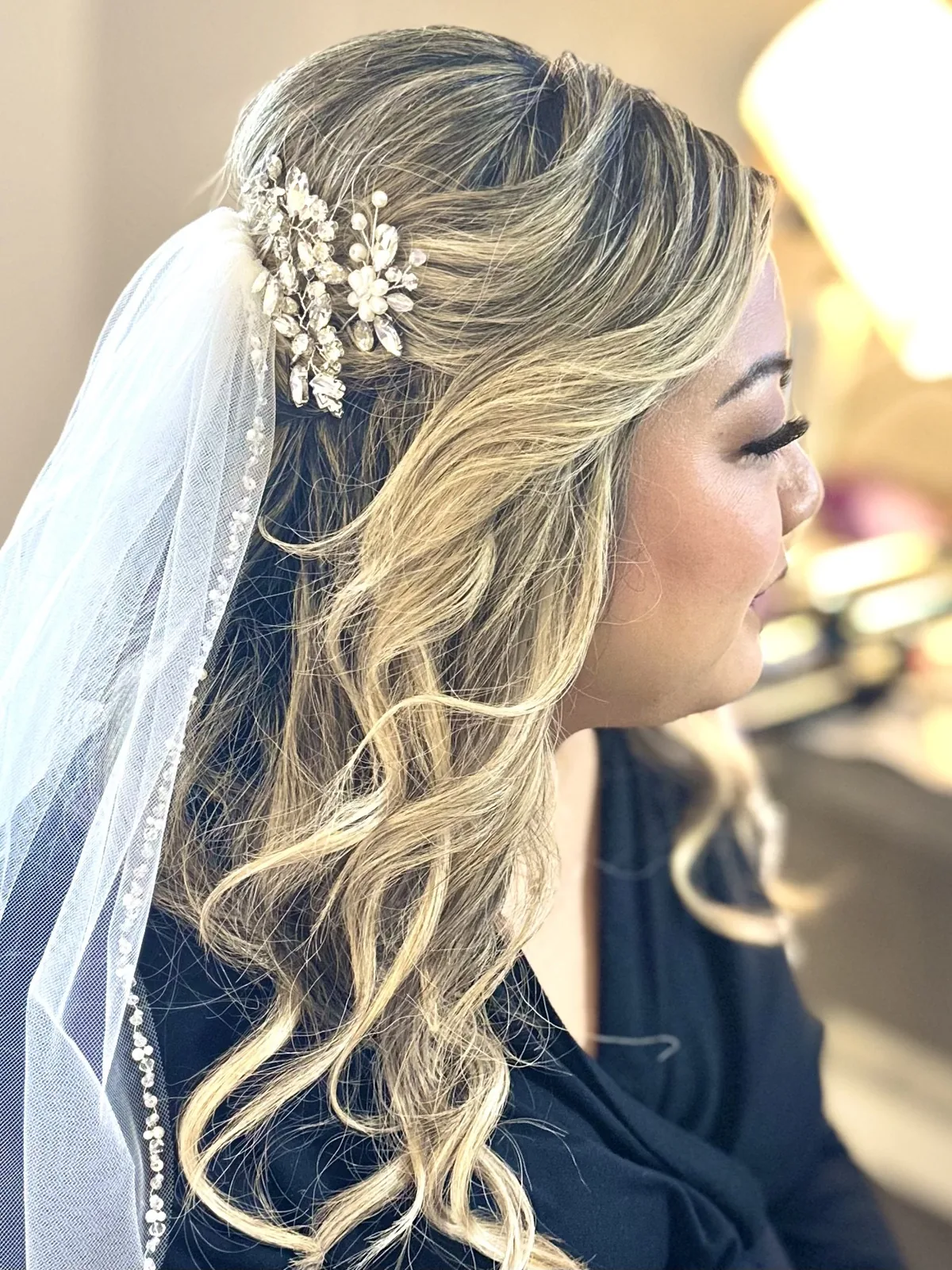 My half-up bridal hairstyle with big blonde curls and a veil.