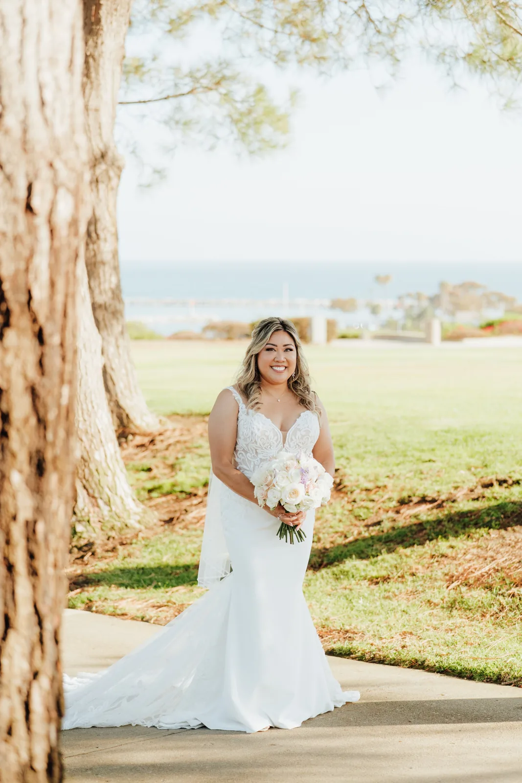 My bridal hair and makeup on Tamara standing beside a coastal lawn in Dana Point.